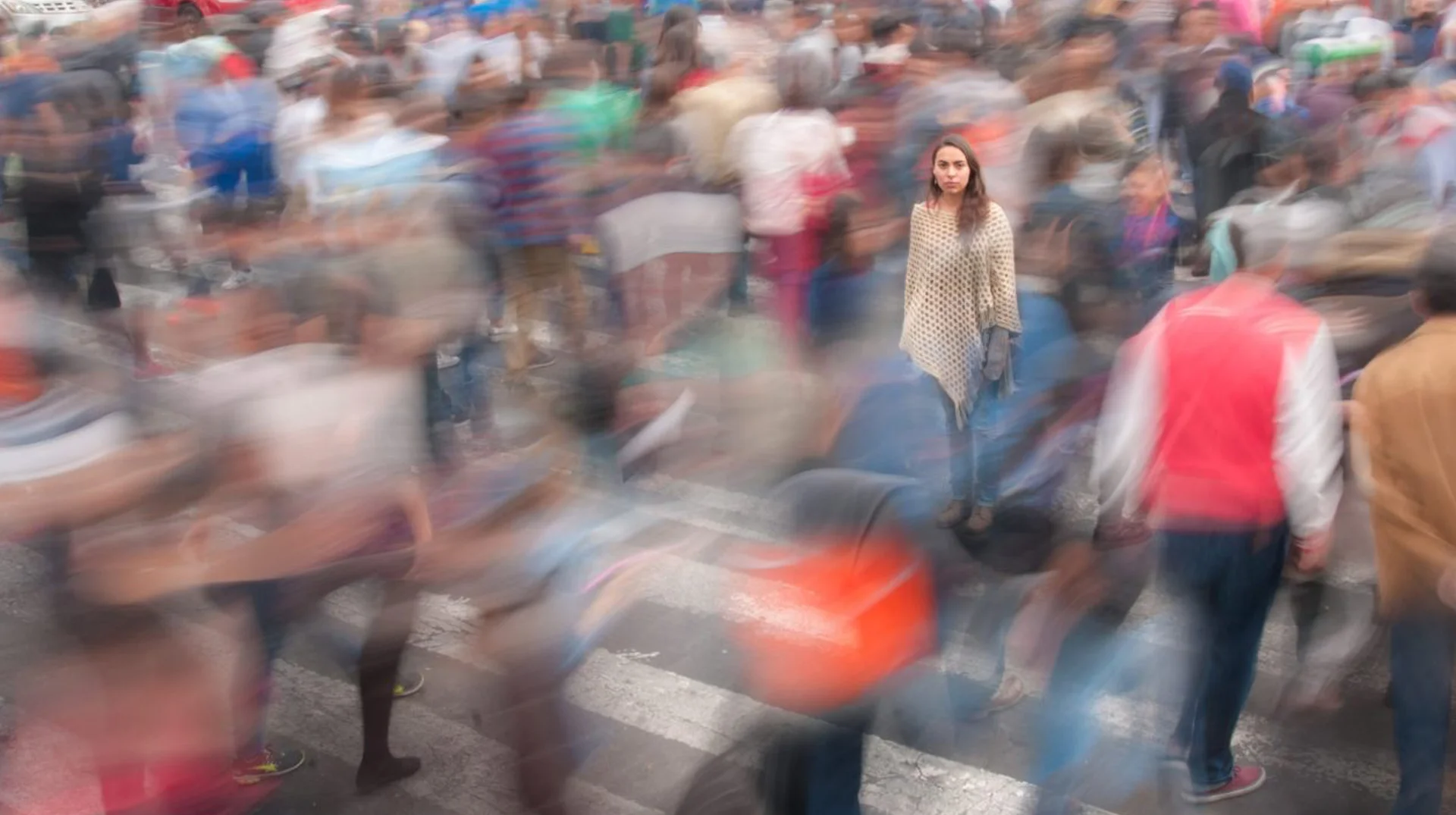 The signature 'real life NPC' visual: a still figure surrounded by a blurred, hurrying crowd, evoking the feeling of a scripted character in a video game.