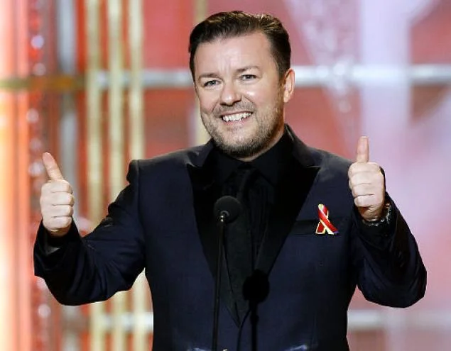 Ricky Gervais delivers his signature grinning double thumbs-up while hosting an awards ceremony.