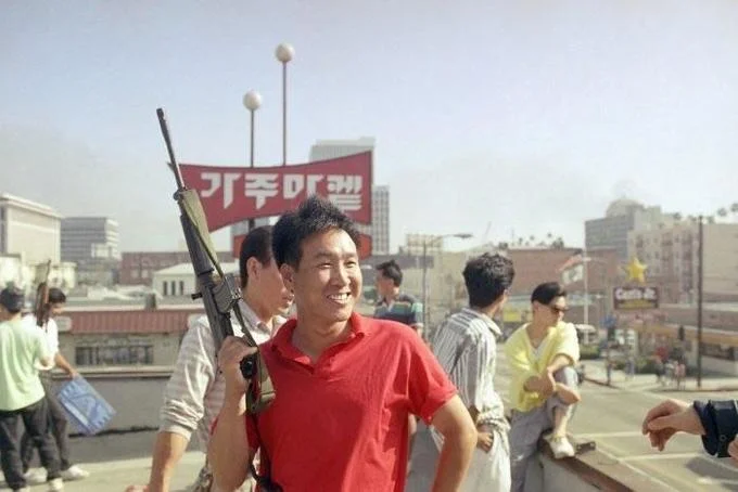 Visually striking Roof Koreans photo contrasting smile with firearm.