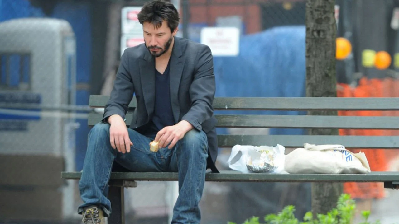 The original 2010 paparazzi photograph of Keanu Reeves eating alone on a Manhattan park bench that launched the 'Sad Keanu' meme.