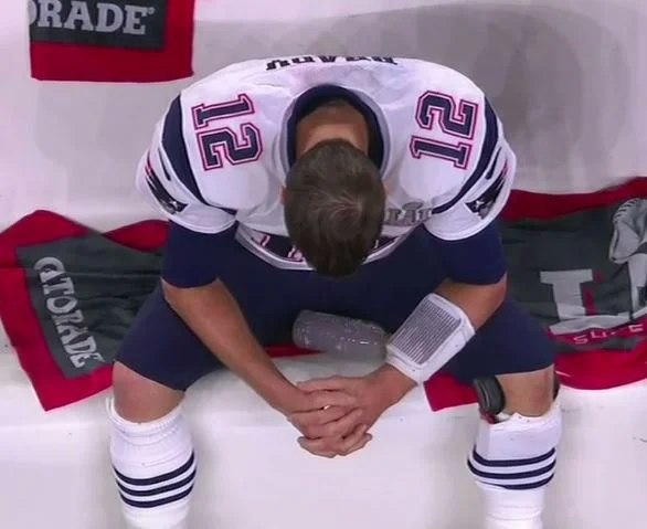 The source photograph of Tom Brady looking dejected on the Patriots bench during Super Bowl LI, which spawned the 'Sad Tom Brady' meme.