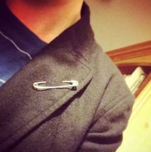 A safety pin worn on a coat lapel as a visible symbol of allyship following the 2016 Brexit vote and U.S. presidential election.