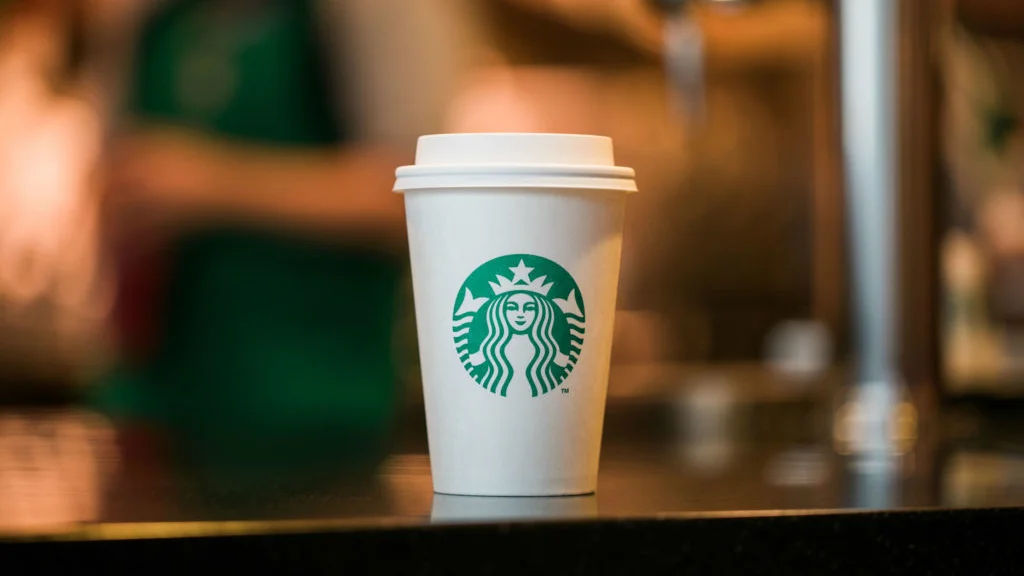 The signature Starbucks paper cup, featuring the brand's green mermaid siren logo, has become synonymous with modern coffee culture and countless internet memes.