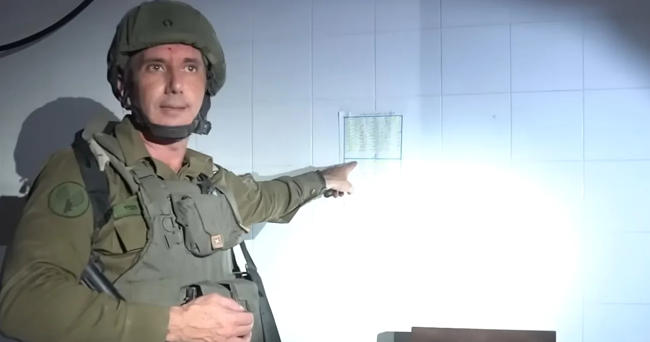 Screenshot from the IDF spokesperson video that popularized the 'There Is a List' meme, showing a soldier gesturing at a paper list posted on a tiled wall.